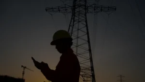 Um engenheiro ao fundo de uma paisagem anotando novas tecnologias elétricas