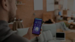 Pessoa segurando um telofone para automação residencial dentro de sua casa.