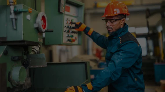 Operador de máquinas e equipamentos com capacete, óculos e luvas de proteção para segurança do trabalho.