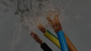 Fios coloridos desencapados em curto-circuito, soltando faíscas.