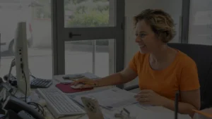Mulher sentada a um computador, administrando gestão escolar eficiente.